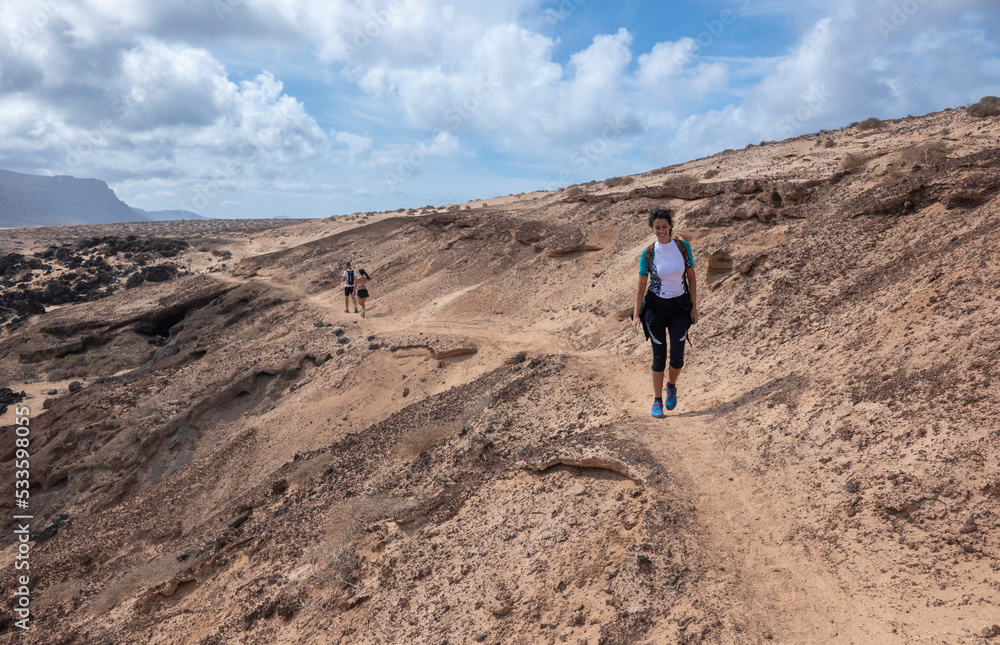 Young woman hiking along the cliffs and unspoiled beaches on the island of La Graciosa, Canary Islands. 