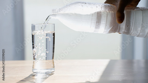 Closeup Holding Water bottle and Pouring water on Glass for drinking. Healthy Concept idea.