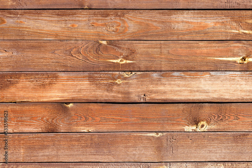 The texture of the wall of old and weathered wooden boards painted with brown paint.