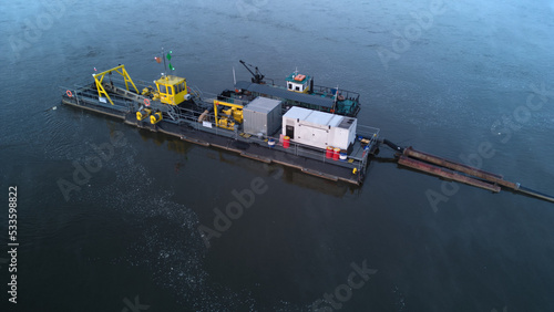 A River Dredger on a river during a misty dusk. Aerial side view.