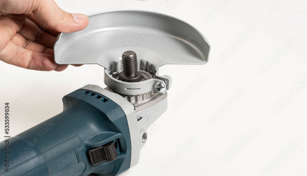 Installing the safety cover on an angle grinder, close-up. Safety precautions when working with construction power tools. Installing the safety cover on an angle grinder, close-up. Safety precautions when working with construction power tools.