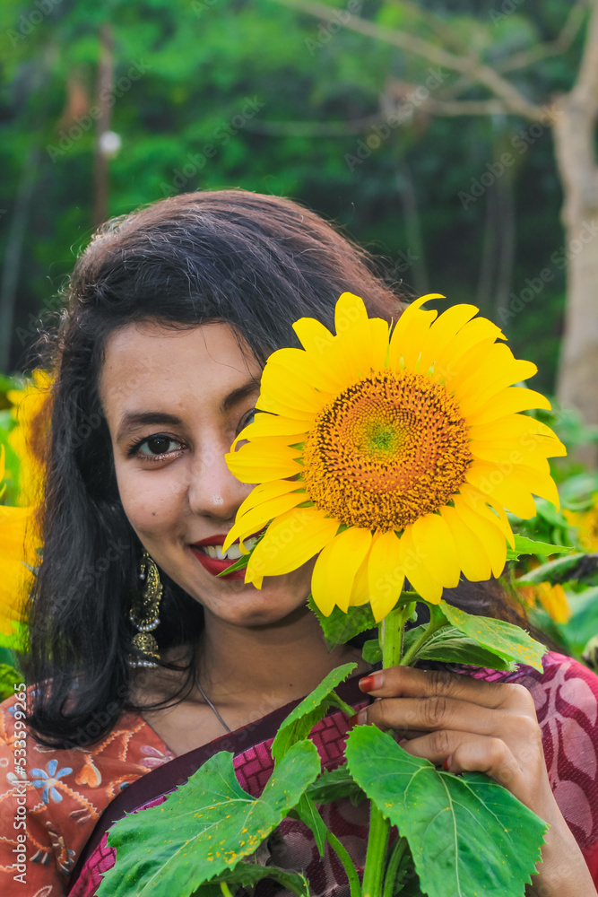 Beautiful young girl enjoying nature on the field of sunflowers. Girl in the field of sunflowers. Girl in a park smiling and covering face with sunflower. Beautiful young girl enjoying nature on the field of sunflowers. Girl in the field of sunflowers. Girl in a park smiling and covering face with sunflower.