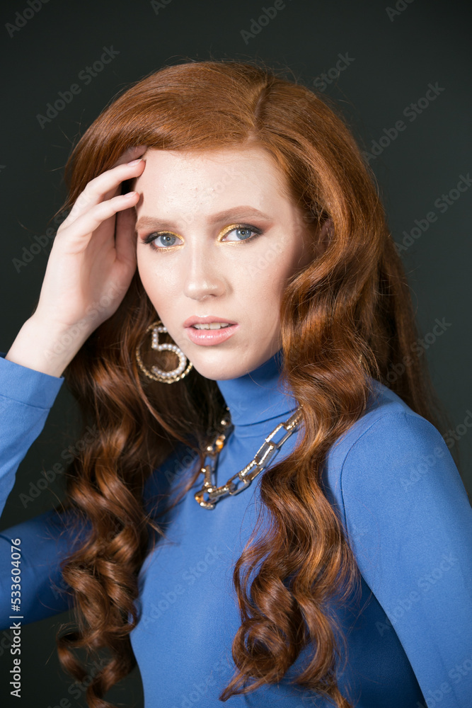red-haired girl in blue clothes with bright makeup and gold jewelry red-haired girl in blue clothes with bright makeup and gold jewelry