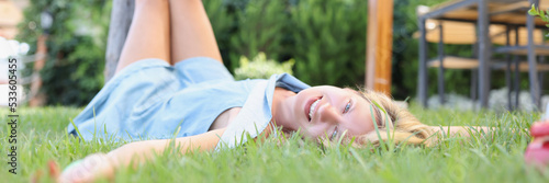 Happy young woman lies on grass in summer
