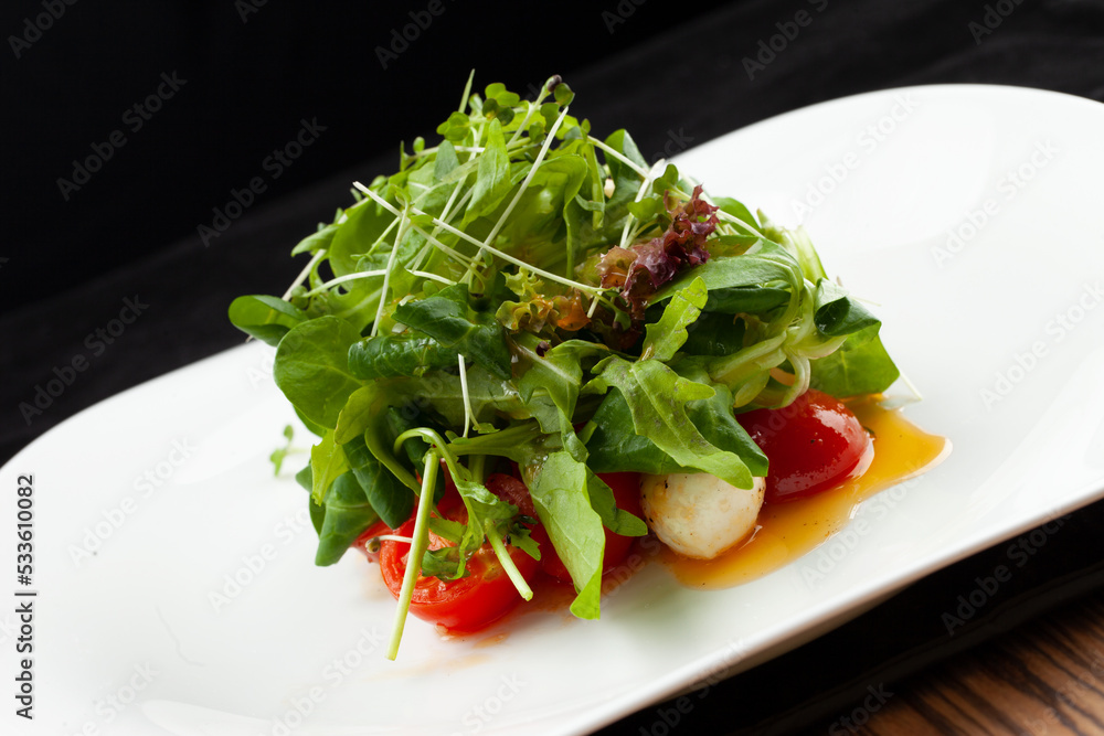 Mini tomatoes, mozzarella balls and greens in a plate. Mini tomatoes, mozzarella balls and greens in a plate.