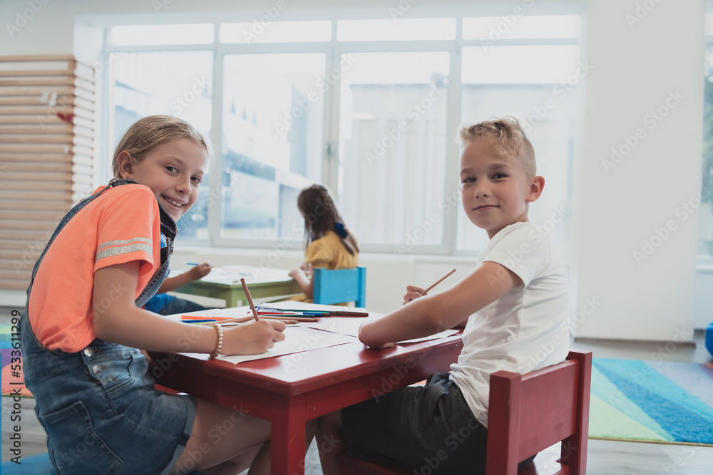 Cute girl and boy sit and draw together in preschool institution Cute girl and boy sit and draw together in preschool institution