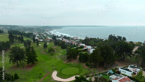 Dolly in aerial view of exclusive houses with their own golf course and tiled roof in a small town with ocean view photo