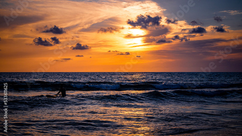 Surfing with the sunset over the sea