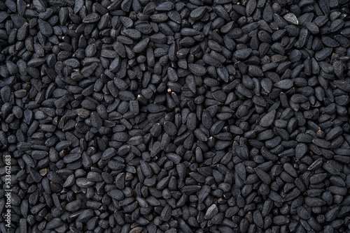 Black cumin macro texture. Whole nigella seeds closeup background. Dry kalonji fruits for food design and cooking. Concept of organic spice and seasoning. Medicinal herb nigella sativa.