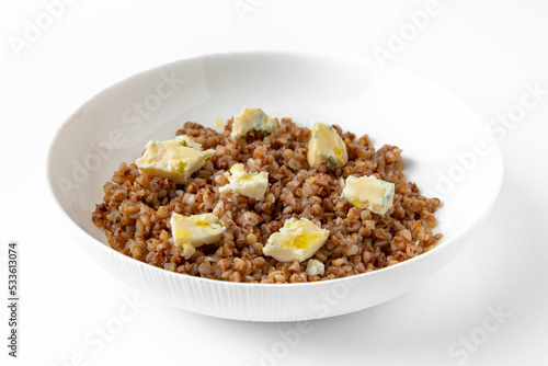 Boiled buckwheat with gorgonzola and olive oil. Balanced, nutritious, tasty and nutritious food. Ready-made menu for a restaurant or for delivery. Dish in a white plate isolated on a white background. © Екатерина