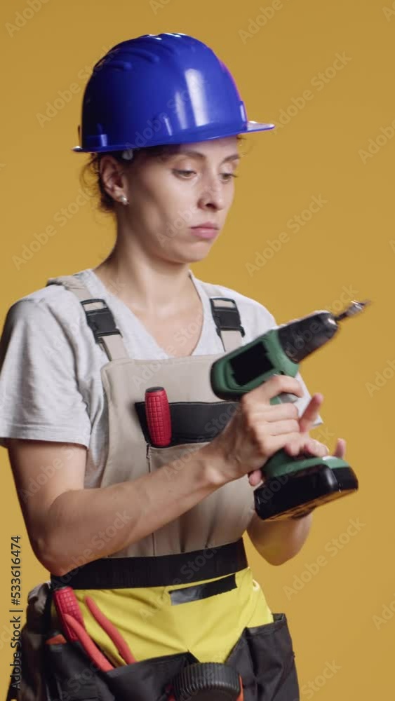 Vertical video: Female constructor working with power drill electric tool or instrument to do deconstruction work and repair. Using drilling nail gun machine to work on refurbishment, atypical Vertical video: Female constructor working with power drill electric tool or instrument to do deconstruction work and repair. Using drilling nail gun machine to work on refurbishment, atypical