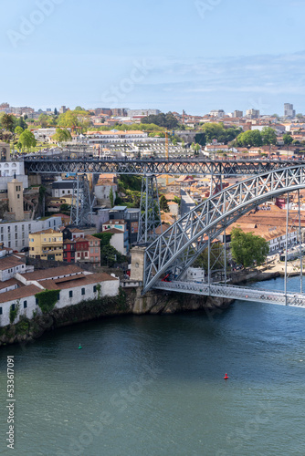 Part of the Dom Luis I bridge in Porto, with people walking on the bridge, on a sunny day.