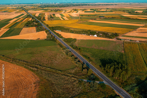 Aerial shot of straight highway through cultivated agricultural fields in Vojvodina, Serbia