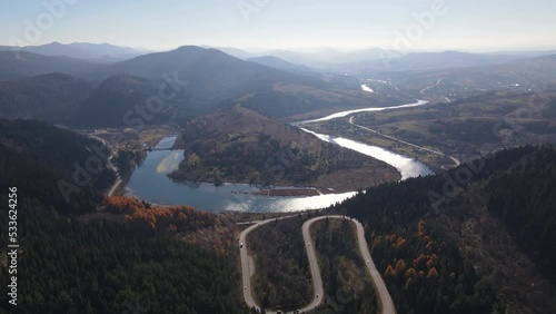 Scenic aerial view of the Carpathian landscape with serpent road and river Stryi among mountains in early autumn, static drone footage photo