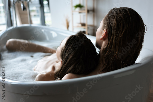 Photos back view of young lesbian women relaxing in bubble bath together