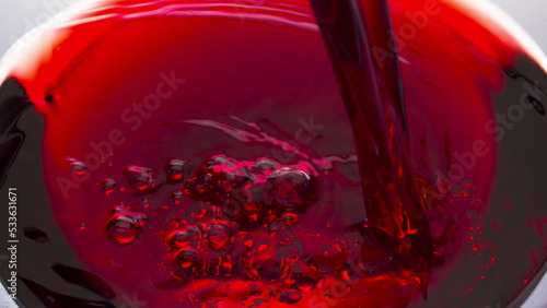 Red wine jet filling glass closeup. Fresh alcoholic liquid swashing wineglass