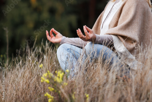 Woman practicing yoga exercise in lotus position. Meditation outdoors
