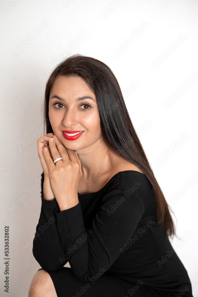 A sensual studio portrait of a beautiful young woman in a black dress with red lipstick on her lips. White background place for text A sensual studio portrait of a beautiful young woman in a black dress with red lipstick on her lips. White background place for text