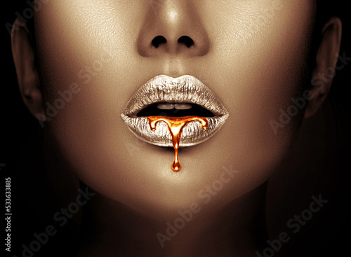 Lipstick dripping. Paint drips, lipgloss dripping from lips, liquid Gold metallic paint drops on beautiful model silver girl's mouth, creative make-up. Beauty woman face makeup close up. Art design 