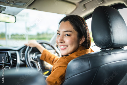 Young beautiful asian women getting new car. she very happy and excited. Smiling female driving vehicle on the road on a bright day. © Chanakon