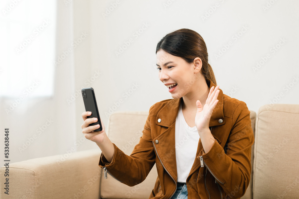 Beautiful young women using mobile phone sitting on sofa in living room. Using smartphone. Woman Shopping online store. Relax time at home Beautiful young women using mobile phone sitting on sofa in living room. Using smartphone. Woman Shopping online store. Relax time at home