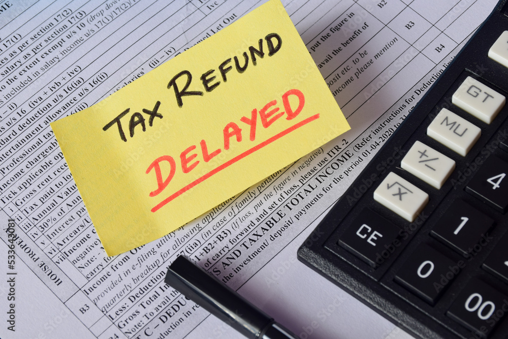 Sticky note with the text Tax Refund Delayed on Income Tax form background with calculator. Sticky note with the text Tax Refund Delayed on Income Tax form background with calculator.