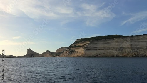 Pov of sailboat bow navigating toward Corsica island cliffs and Capo Pertusato lighthouse in France, 50fps photo