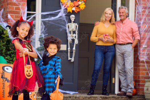 Portrait Of Grandchildren Dressing Up To Visit Grandparent's House Trick Or Treating On Halloween