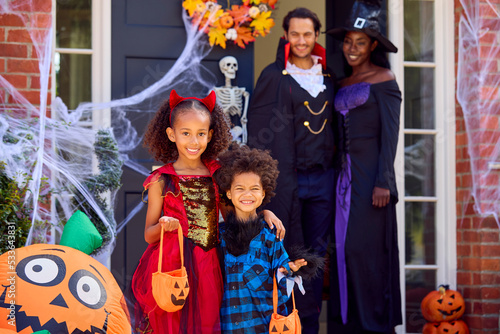 Portrait Of Family Dressed Up For Halloween Outside House Ready For Trick Or Treating
