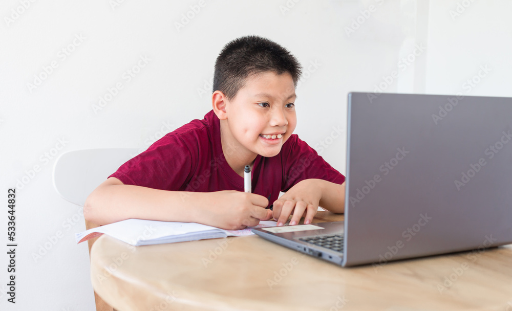 Asian boy studying online on computer laptop with smiling and happy face at home. online education and e-learning concept. Asian boy studying online on computer laptop with smiling and happy face at home. online education and e-learning concept.