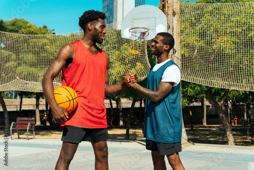 One vs one basketball game training at the court. Cinematic look image of friends practicing shots and slam dunks in an urban area