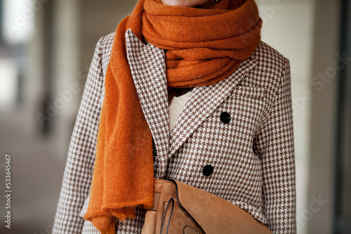 Close up knitted wool ochre scarf and double breasted houndstooth jacket with buttons. Stylish fashion trend details photo