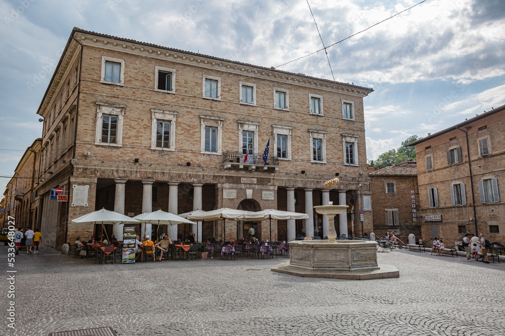 Urbino, Marche, Italy - July 2021: central historical square with medieval buildings and open air cafe in the city of Urbino, Marche, Italy.