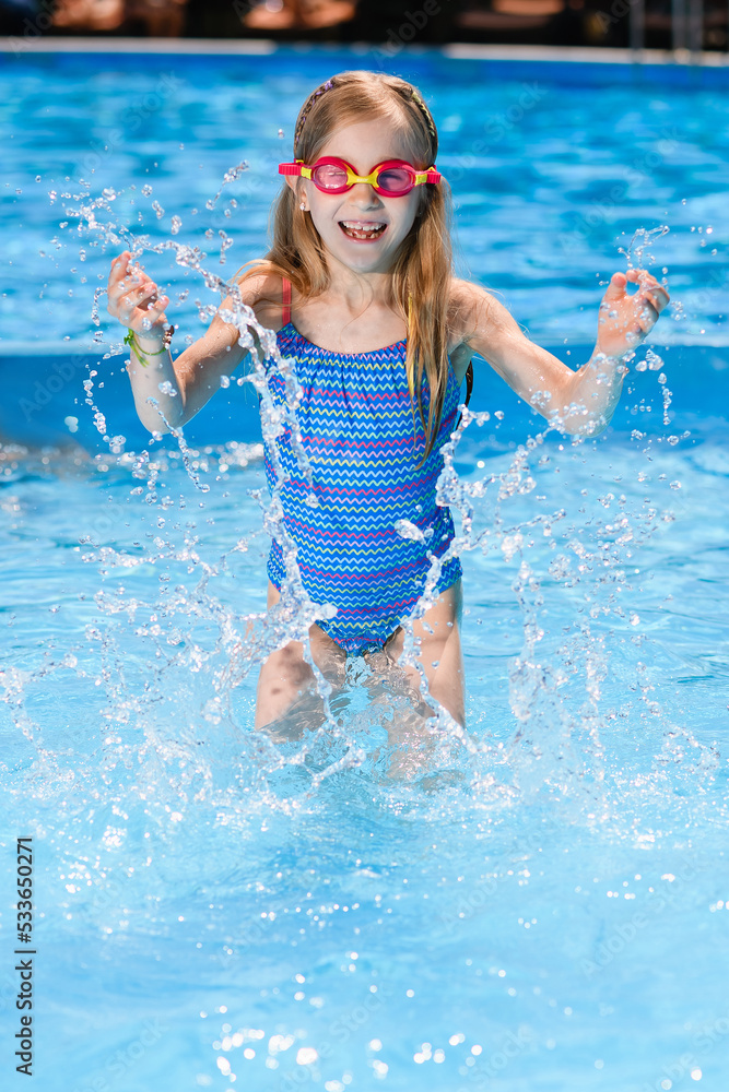 Little girl in pool with water splashes