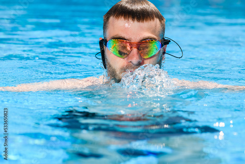 Professional male swimmer in goggles in pool