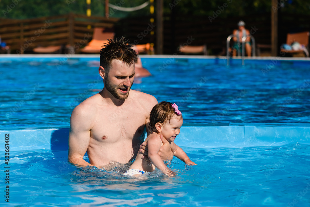 Father teach baby to swim in pool