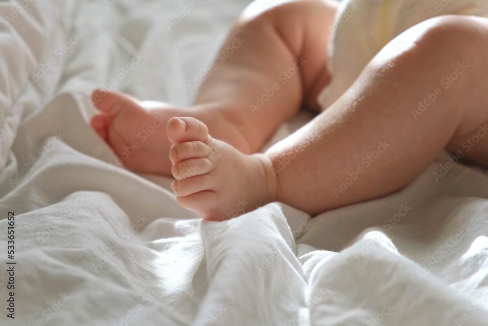 Baby Legs Close up on White Blanket. Healthy Newborn Feet. Warm Sunlight. Beautiful Shot of Infant's Small Feet on a Light Background. Early age children development. Authentic Candid Lifestyle. Baby Legs Close up on White Blanket. Healthy Newborn Feet. Warm Sunlight. Beautiful Shot of Infant's Small Feet on a Light Background. Early age children development. Authentic Candid Lifestyle.