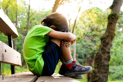 lonely boy crying sitting in the forest. children mental health concept.