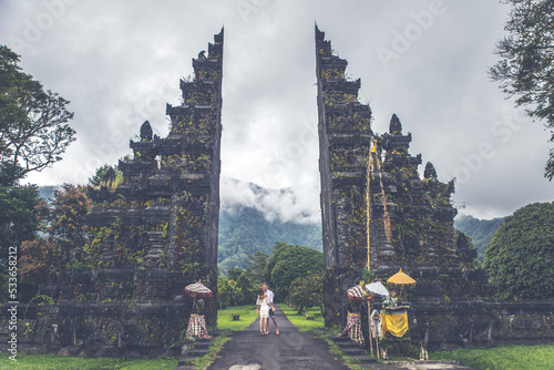 Happy couple spending time at the handara's gate in bali. walking on the street to the historic door