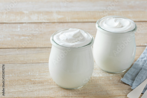 fresh greek yogurt in glass jar  healthy breakfast concept  wooden background  copy space