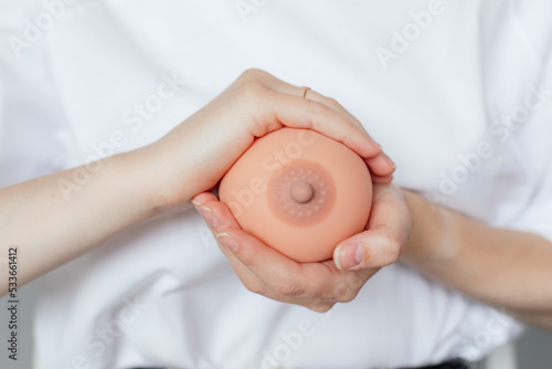 Photo of hands holding model of female breast closeup, free copy space. Training for pregnant women with qualified lecturer. Online study, practice on dummy, breast feeding, newborns care