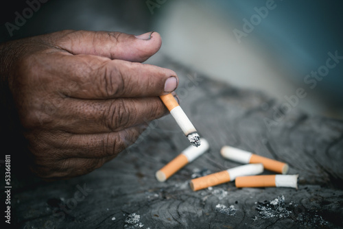 Close-up of old man holding a cigarette in his hand, Elderly man is holding a burning cigarette while smoking.