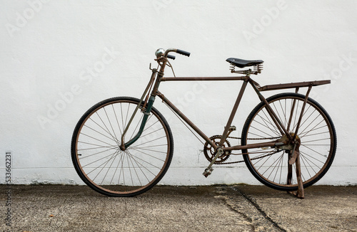 Vintage old bike standing against white wall background © Pituk
