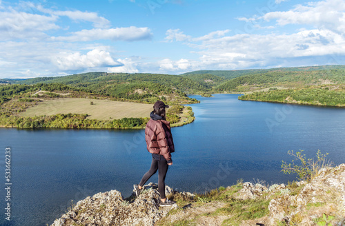 Young woman walking outdoor in the nature high above a lake with stunning view . Pchelina lake in Bulgaria .Scenic landscape  photo