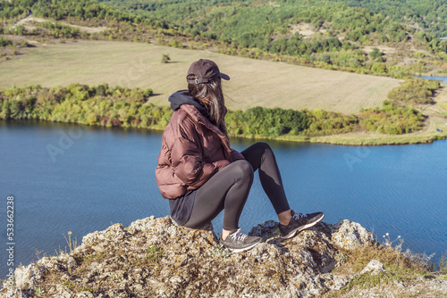 Traveler woman sitting on a rock high above a blue lake .Traveling in the autumn  nature in Bulgaria	. Pchelina Lake  photo
