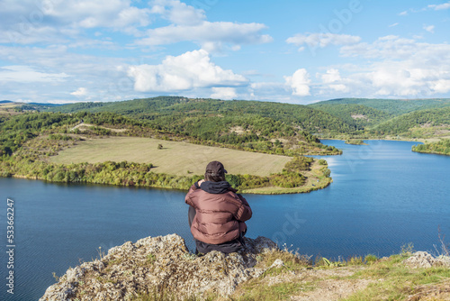 Traveler woman sitting on a rock high above a blue lake .Traveling in the autumn  nature in Bulgaria	. Pchelina Lake  photo