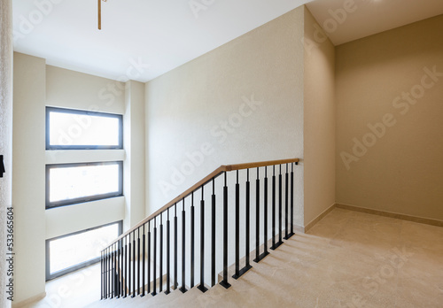 stairs made of tiles in a new house. metal black railing with wooden handrails