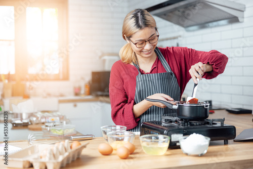 Beautiful young woman  is mixing batter  looking at camera and smiling while baking in kitchen at home  decorating a cake of chocolate cake cooking class  culinary  bakery  food and people concept