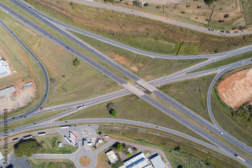 Aerial view of the Dom Pedro Highway at the height of the city of Itatiba. Industries, cars on the highway and vegetation on the side of the road. Aerial view of the Dom Pedro Highway at the height of the city of Itatiba. Industries, cars on the highway and vegetation on the side of the road.