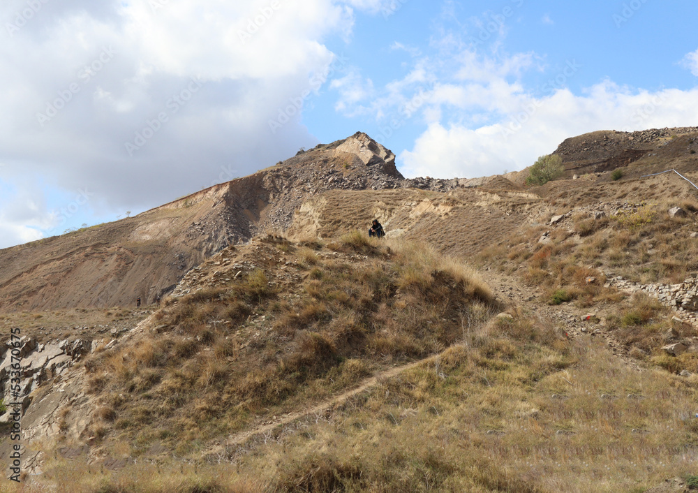 person up on a hill in a rocky landscape person up on a hill in a rocky landscape